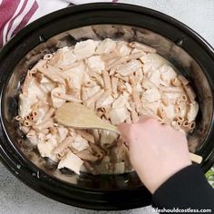 someone is stirring some food in the crock pot with a wooden spoon and it's ready to be cooked