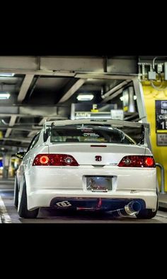 the back end of a white car parked in a parking garage