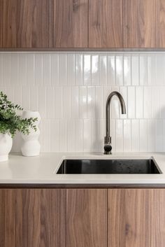 a kitchen sink with two white vases on the counter