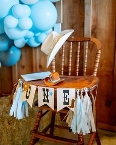 a wooden chair sitting next to a table covered in blue and white streamers with hats on it