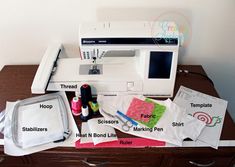 the sewing machine is sitting on top of the table next to it's contents