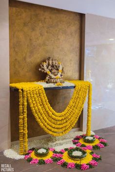 a decorated table with flowers and garlands on the floor in front of a wall