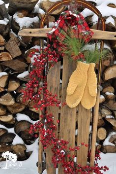 a wooden sled filled with lots of red berries next to a pile of logs