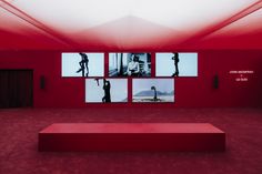 a red room with multiple pictures on the wall and a bench in front of it