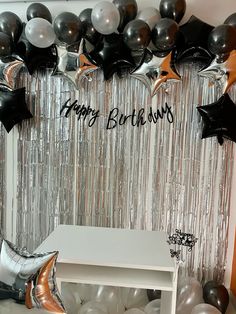 a birthday party with balloons and streamers on the wall, silver foil curtains and black and white decorations