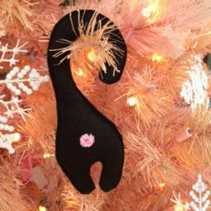 a black cat ornament hanging on a pink christmas tree