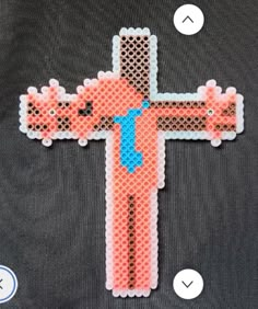 a cross made out of perler beads on top of a black shirt with white circles around it