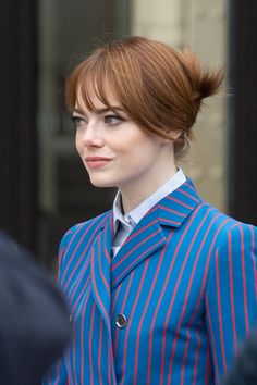 a woman with red hair wearing a blue striped jacket