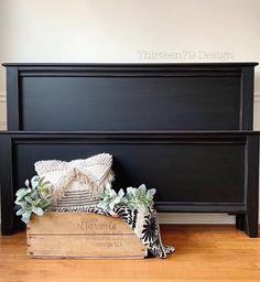 an old dresser is painted black with white flowers and greenery on the bottom shelf