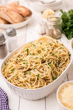 pasta with parmesan cheese and herbs in a white dish on a wooden table