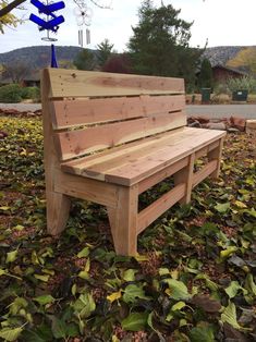 a wooden bench sitting on top of leaves in front of a tree with blue arrows hanging from it