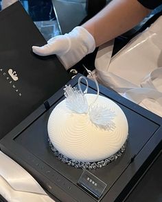 a person in white gloves is decorating a cake