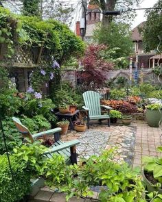 an outdoor garden with lots of plants and chairs