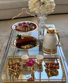 a glass table topped with lots of different types of desserts and pastries next to a vase filled with flowers