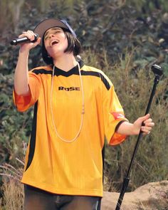 a young boy singing into a microphone while wearing a yellow shirt