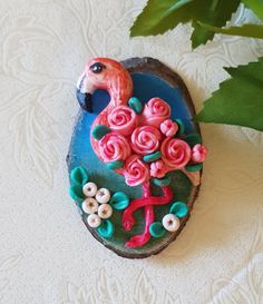 a pink flamingo sitting on top of a blue plate next to a green plant