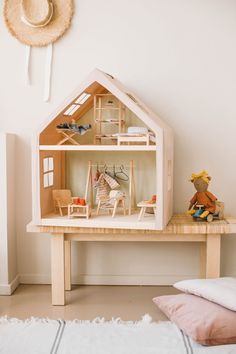 a doll house sitting on top of a wooden table next to a stuffed animal toy