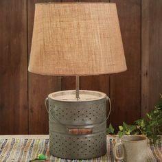 a table lamp sitting on top of a wooden table next to a green pail