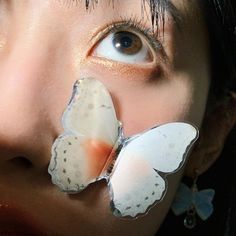 a close up of a person with butterfly decorations on their face and nose, looking at the camera