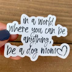 someone holding up a sticker that says in a world where you can be anything, be a dog mom