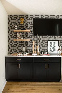 a black and white wallpaper with gold accents in a dining room area that has wooden flooring