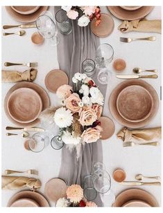 the table is set with plates, silverware, and flowers on top of it