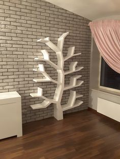 a room with a brick wall and wooden flooring next to a white tree sculpture