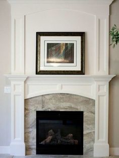 a white fireplace with a painting on the mantle and a potted plant in front of it