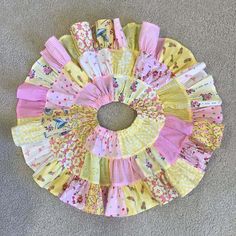 a circular piece of fabric on the floor with pink and yellow fabrics in it's center