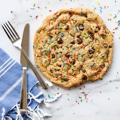 a chocolate chip cookie with sprinkles on it next to a fork and knife