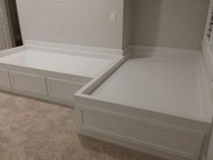 a white bed frame with drawers in a room