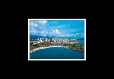 an aerial view of the city and beach from above, with blue water in the foreground