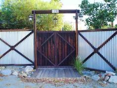 a wooden gate with two gates on each side and rocks in the foreground behind it