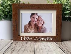 a wooden frame with the words mother and daughter on it next to potted plants