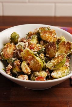 a white bowl filled with brussel sprouts on top of a wooden table