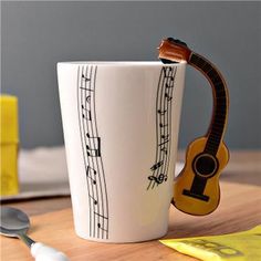 a white coffee cup with musical notes on it and a wooden spoon next to it