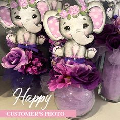 two vases filled with purple flowers and stuffed elephants on top of eachother