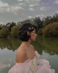 a woman in a pink dress is sitting by the water