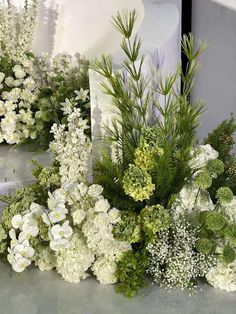 white flowers and greenery are arranged on the floor