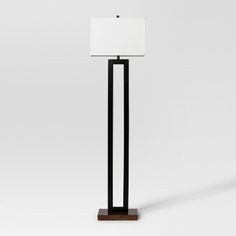 a lamp that is on top of a wooden stand with a white shade over it