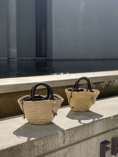 The Camille bag is our very modern version of the traditional Panier basket in a mini size. The basket, handmade by artisans in Spain in palm leaf straw, is covered in a metallic silver mesh, and the short handles coiled in black leather. It is lined in black cotton fabric, with leather drawstring with metal star charms. The bag is finished with a Cuckoo B keychain featuring a buffalo horn star made in Vietnam, a handmade in Argentina ceramic white star and the Cuckoo B bronze tag. It is inspire Luxury Straw Basket Bag With Braided Handles, Luxury Black Straw Bag With Braided Handles, Luxury Black Woven Straw Bag, Luxury Summer Basket Bucket Bag, Luxury Basket-shaped Bucket Bag For Summer, Luxury Handwoven Straw Basket Bag, Luxury Handwoven Basket Straw Bag, Luxury Straw Bucket Bag With Braided Handles, Luxury Black Straw Bag For Summer