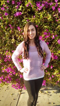 a woman standing in front of some purple flowers