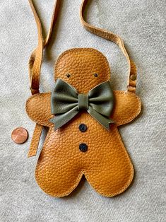 a brown leather bag with a bow and a ginger on it's side, next to a penny