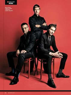 three men in suits sitting on top of a wooden chair with their arms crossed and legs crossed