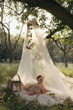 a woman sitting in the grass under a canopy