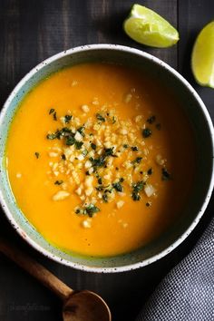 a white bowl filled with carrot soup and garnished with parsley