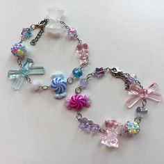 a colorful bracelet with candy charms and bows on it's chain is laying on a white surface