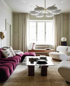 a living room with couches, chairs and a coffee table in front of a window