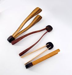 four wooden utensils are lined up on a white surface, one is black and the other is brown