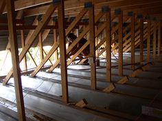 a man is working on the floor in an unfinished room with wooden beams and plywood